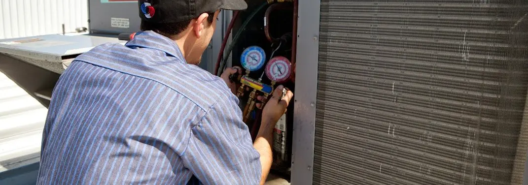 HVAC technician servicing a condenser unit in Big Stone Gap